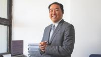 Dr. Daichi Shimbo wearing a gray suit pictured in his office.